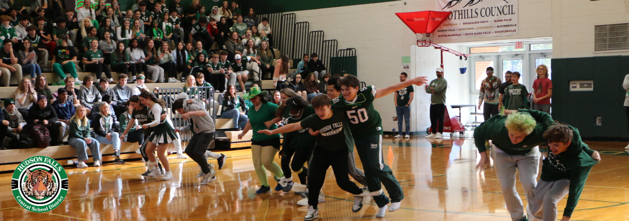 Photo of high school students doing three legged race at pep rally in the gym