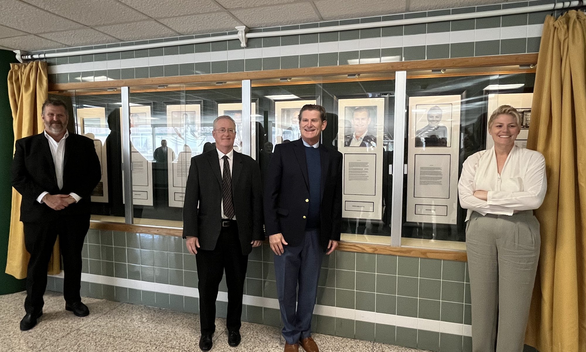 Photo of Wall of Distinction inductees in front of their photos on the wall