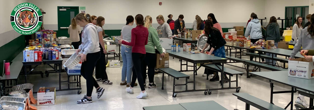 Photo of High School Student Council organizing food donations in the small cafeteria for Thanksgiving food drive.