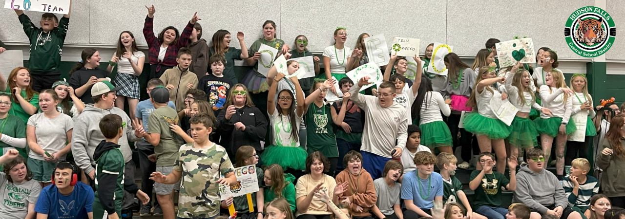 Photo of seventh graders in the bleachers of the gym full of green and white for Pep rally