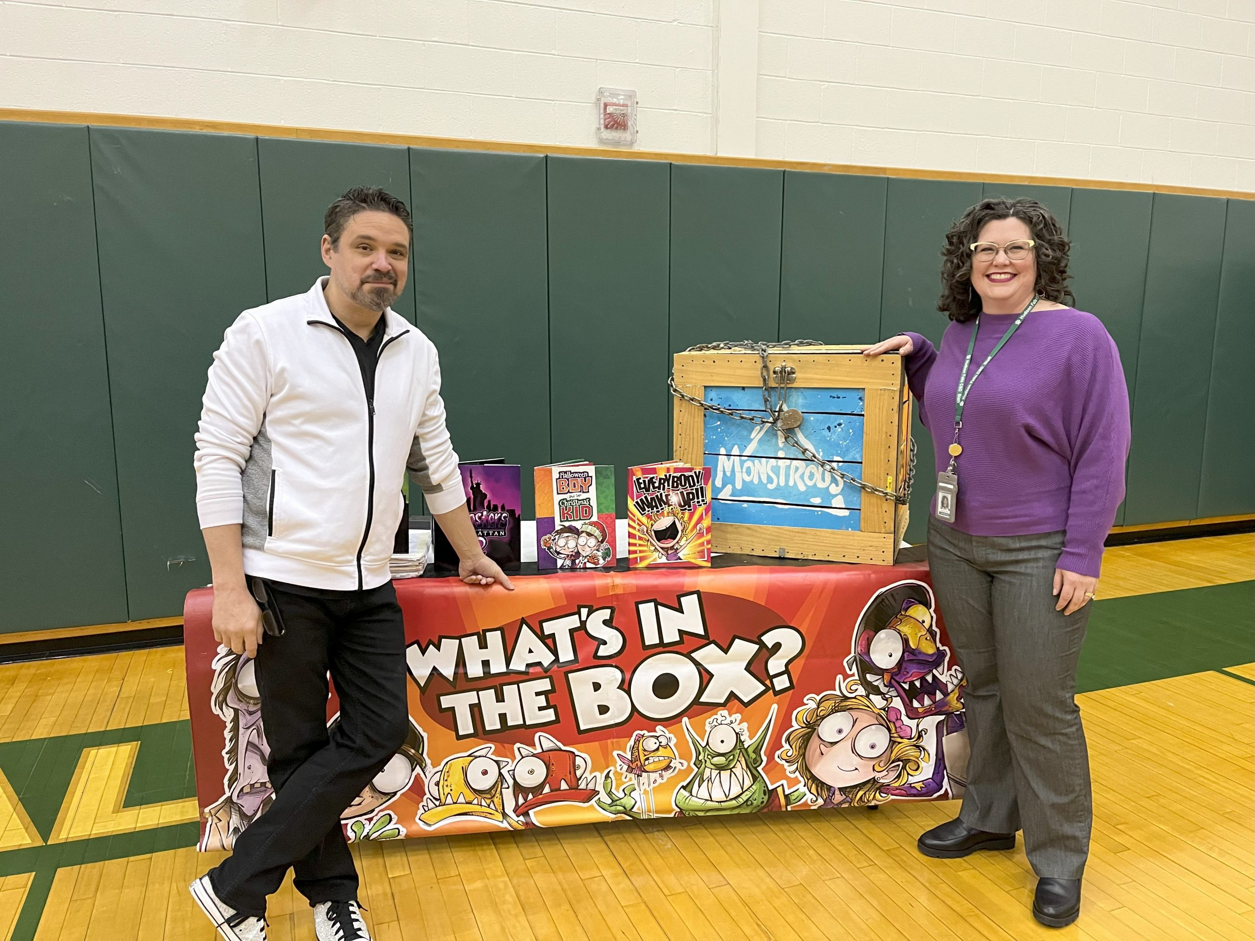 Photo of author Daniel Jude Miller and Mrs. Craner in front of a whats in the box table.