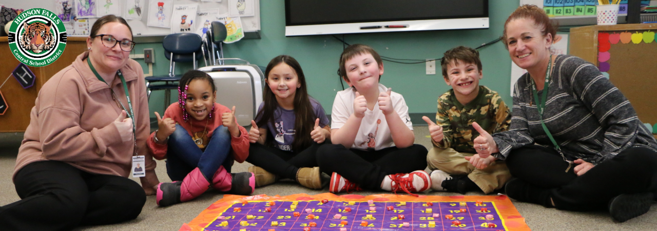 2 teachers and 4 students sitting with thumbs up